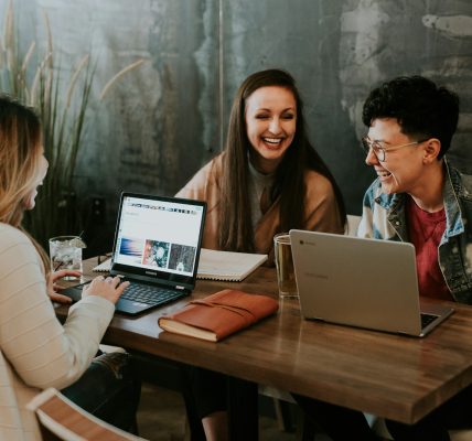 three people sitting in front of table laughing together