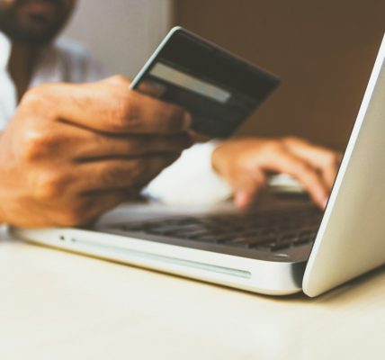 person using laptop computer holding card