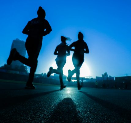 silhouette of three women running on grey concrete road