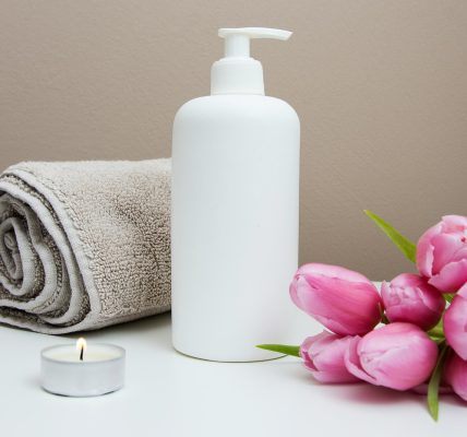 white plastic pump bottle beside pink tulips and gray towel
