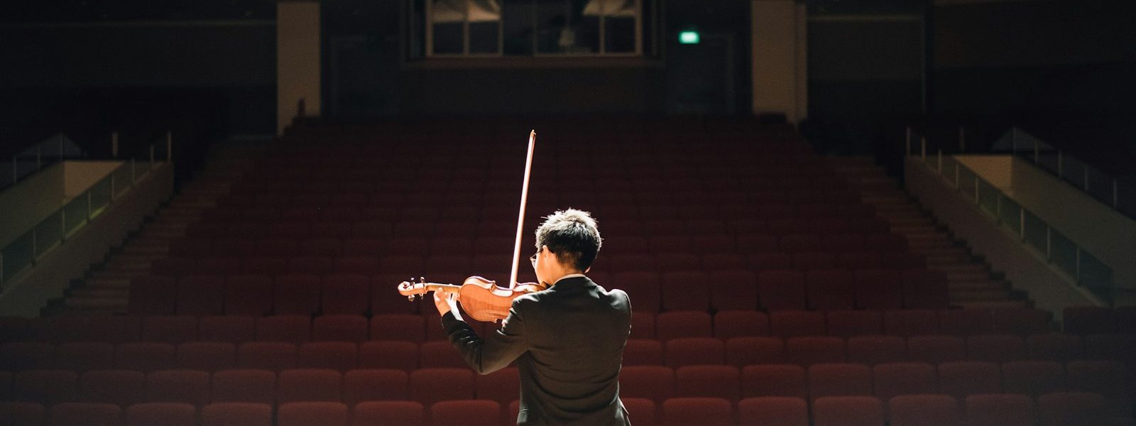 man standing in front of stage playing violin