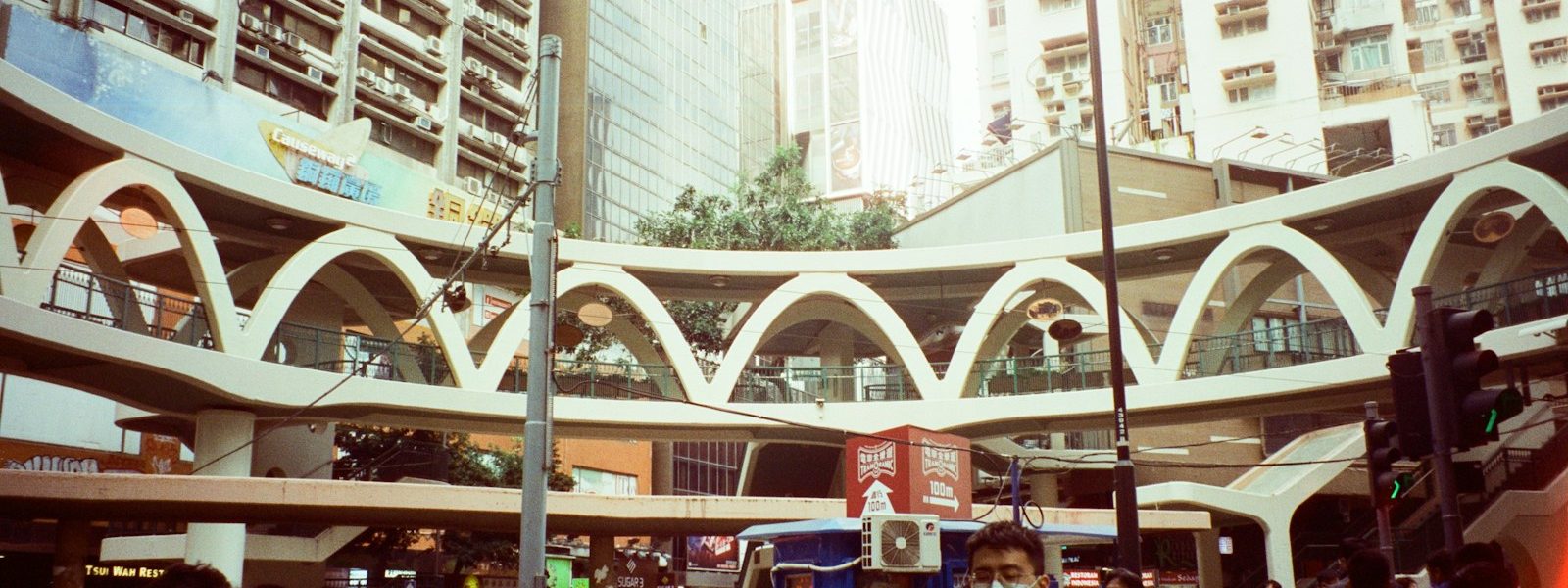 a group of people walking down a street next to tall buildings