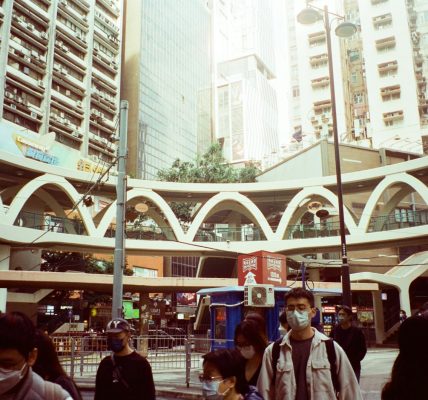 a group of people walking down a street next to tall buildings