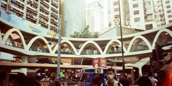 a group of people walking down a street next to tall buildings