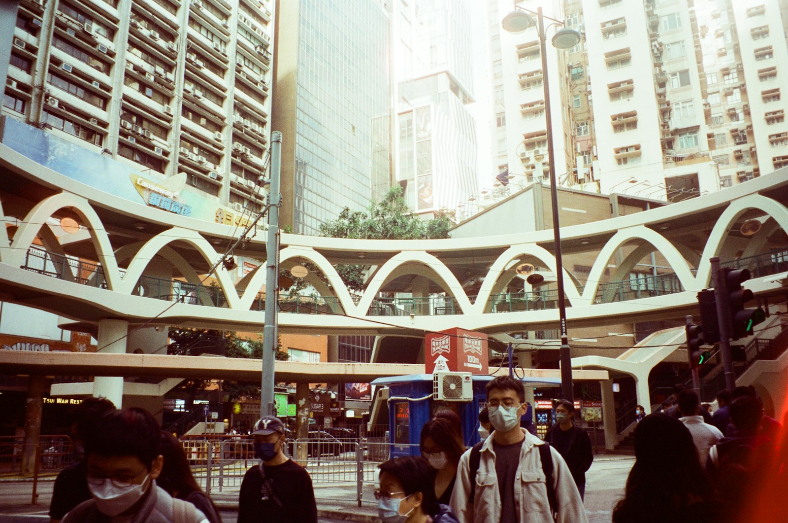 a group of people walking down a street next to tall buildings