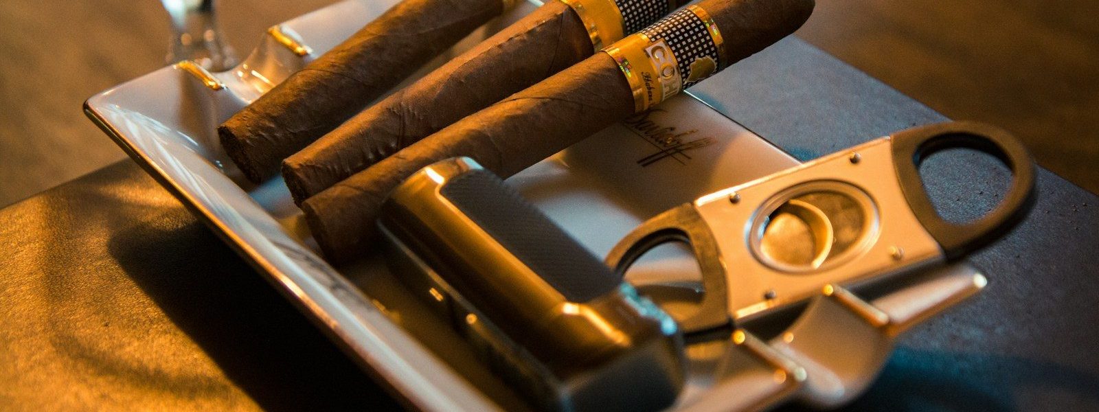 three cigar beside cutter on ashtray