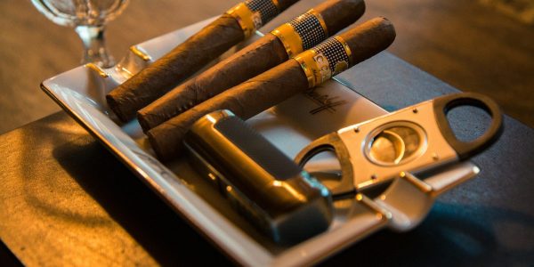 three cigar beside cutter on ashtray
