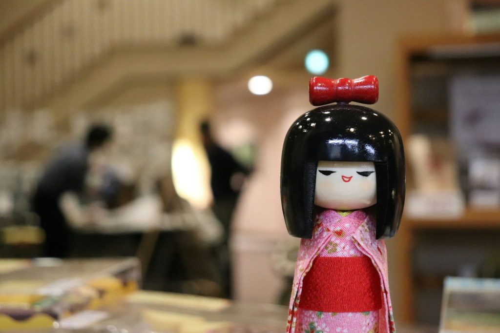 A japanese kokeshi doll is in focus.