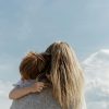 woman holding child from behind against cloudy sky