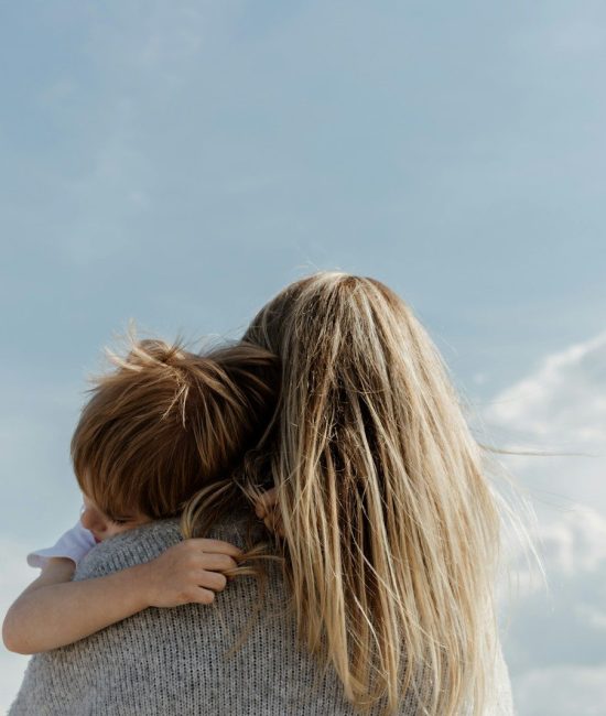 woman holding child from behind against cloudy sky