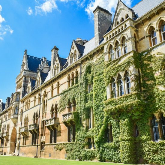 Gothic revival building with ivy-covered stone walls under a bright blue sky