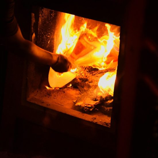 A person places a pizza into a wood-fired oven