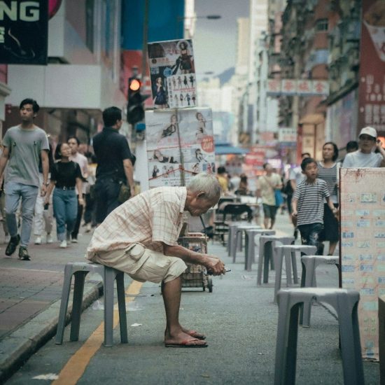 man seating on gray plastic stool
