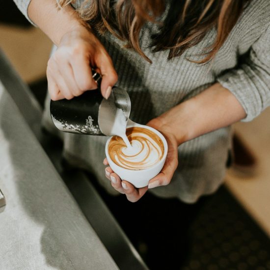 person pouring cup of coffee in white ceramic cup