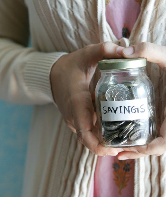 a woman holding a jar with savings written on it