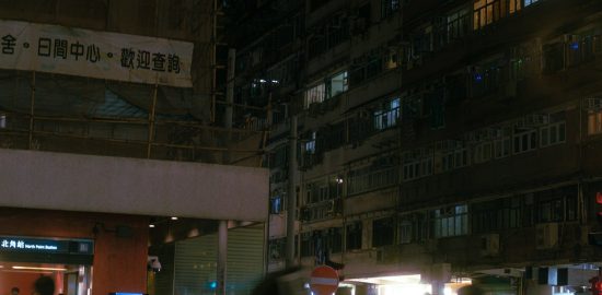 A dense residential building at night above the North Point Station entrance in Hong Kong